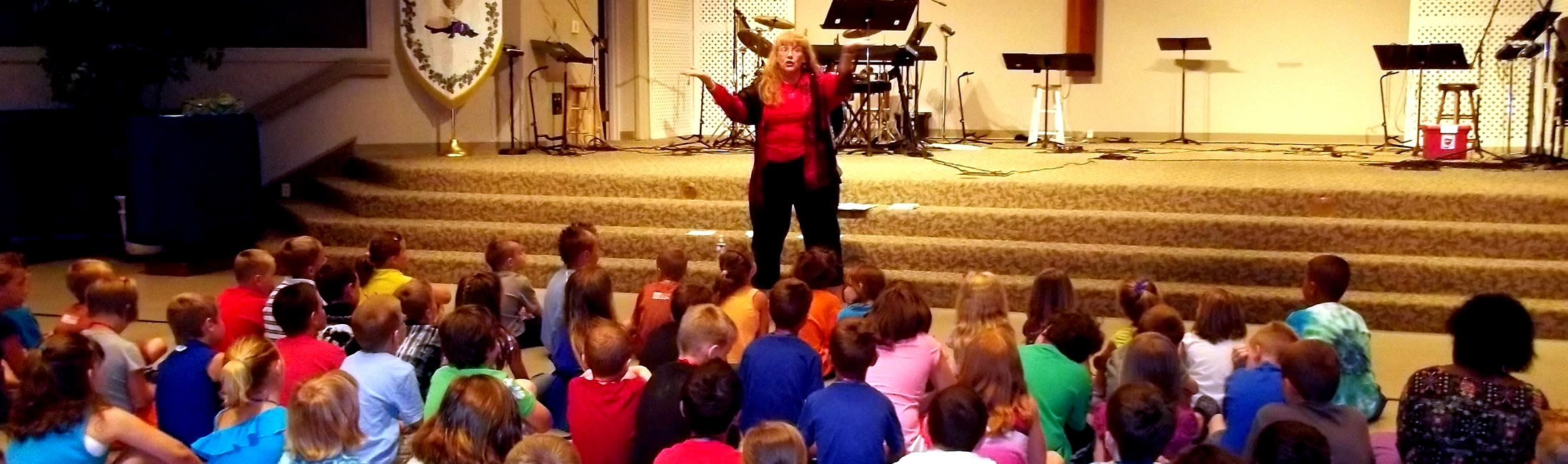 Chautauqua header scholar lecturing children in auditorium